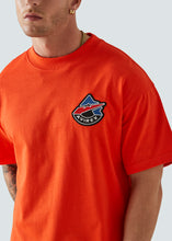 Load image into Gallery viewer, Orange Avirex t-shirt with embroidered logo close up
